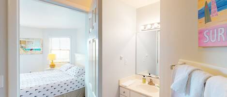 A bedroom with a bed, a bedside table with a lamp, and a window with blinds.