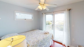 A bedroom with a bed, a ceiling fan, a window with curtains, and a view of the outdoors. - Oceanfront home with incredible beach views, washer/dryer & pool (Avon)