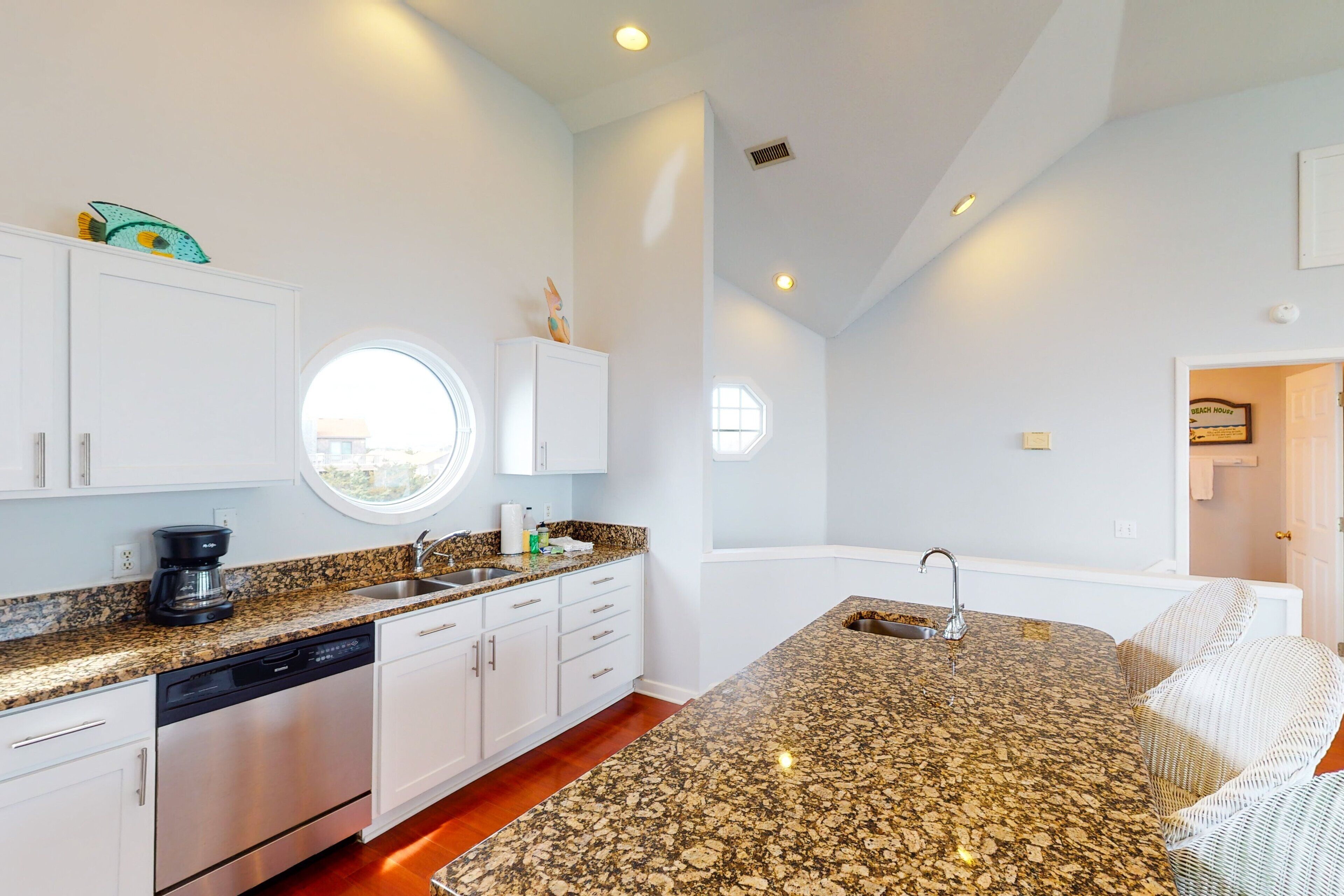 A modern kitchen with granite countertops, white cabinetry, and a built-in dishwasher.