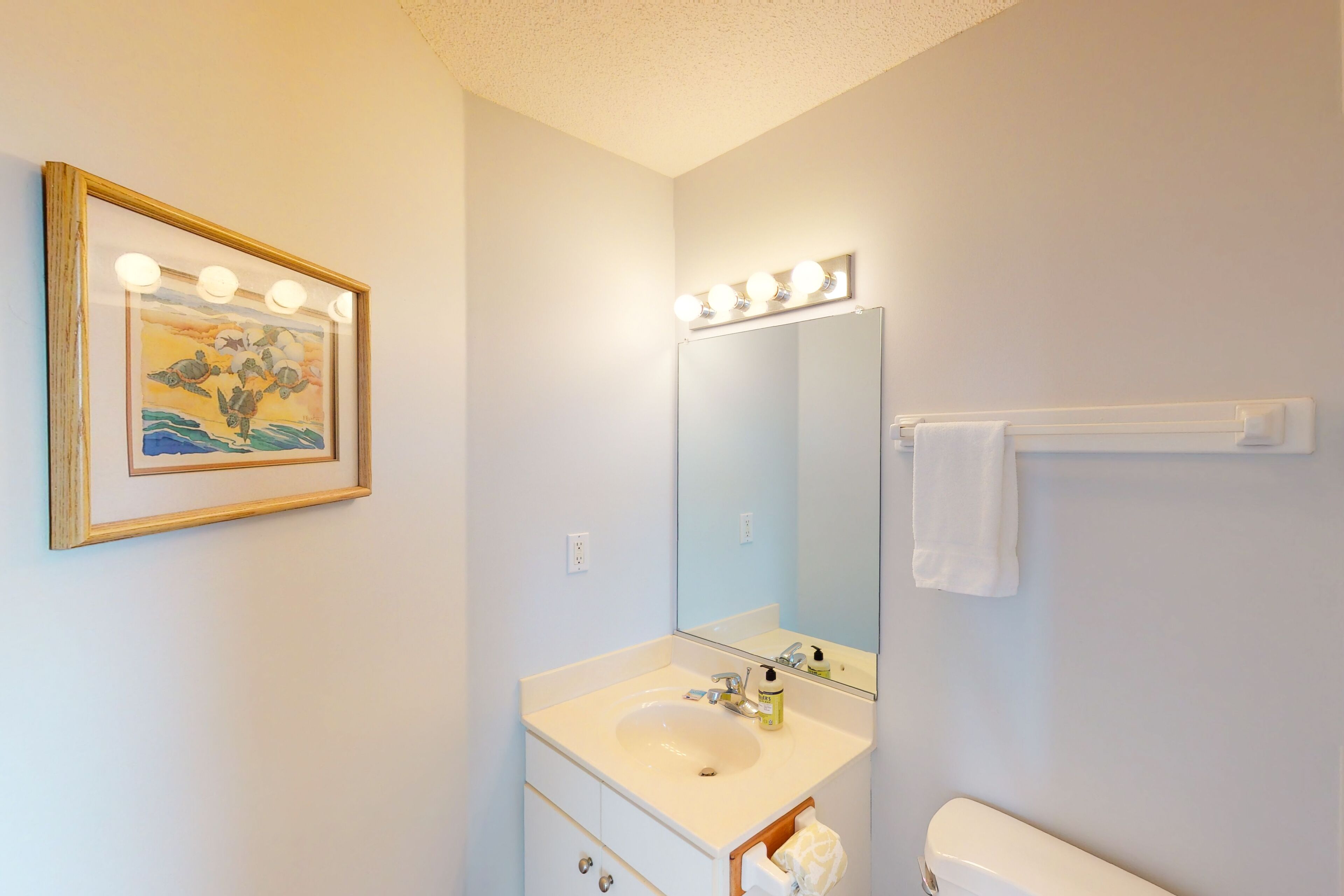 A bathroom with a sink, mirror, and lights above the mirror.