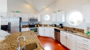 A modern kitchen with white cabinets, granite countertops, stainless steel appliances, and a large window. - Oceanfront home with incredible beach views, washer/dryer & pool (Avon)