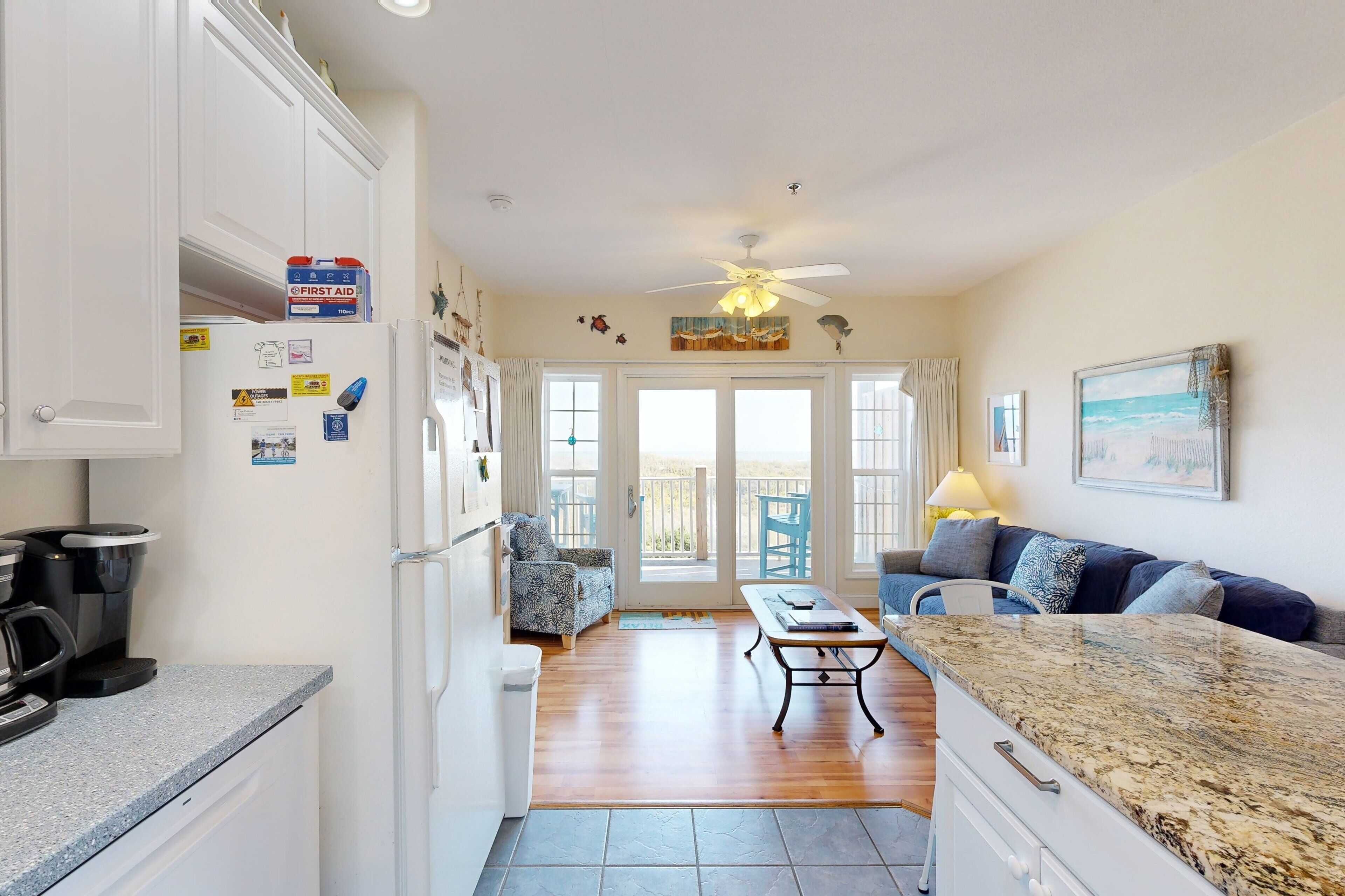 A kitchen with a refrigerator, coffee maker, and a dining area with a table and chairs.