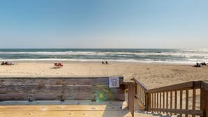 A beach view from a wooden deck with a sign instructing to pick up pets after use. - Inviting beachfront condo featuring hot tub & pool, central AC, elevator, & deck (Hatteras)