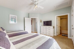 Ein Schlafzimmer mit zwei Betten, einem Deckenventilator, einem Schminktisch und einem Fernseher.