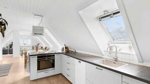 A modern kitchen with white cabinets, a black countertop, and a skylight. - 5 Star Holiday Home in Svaneke (Svaneke)