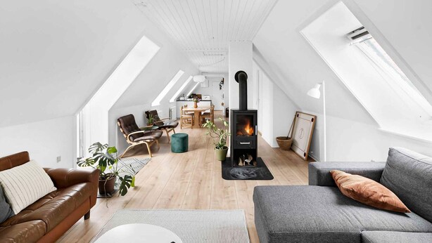 A spacious loft with high ceilings, skylights, a central fireplace, and a cozy seating area with leather sofas and a dining table. - 5 Star Holiday Home in Svaneke (Svaneke)