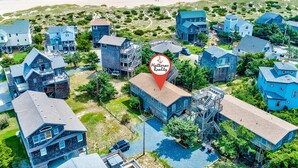 Uma área residencial costeira com várias casas, incluindo uma casa em destaque com um alfinete vermelho indicando um anúncio imobiliário.