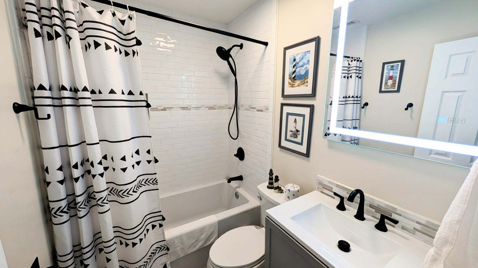 Un baño con ducha, inodoro, lavabo y espejo con marcos de fotos.