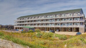 Un hotel a più piani con balconi, una spiaggia sabbiosa di fronte e un cielo sereno.
