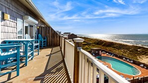 Un balcone con vista sulla spiaggia e sull'oceano, arredi da esterno e una piscina.