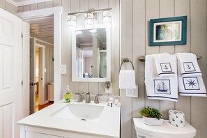 A bathroom with a white sink, a large mirror, and a towel rack with towels. - Dog-friendly coastal home with large yard and close to beach (Supply)