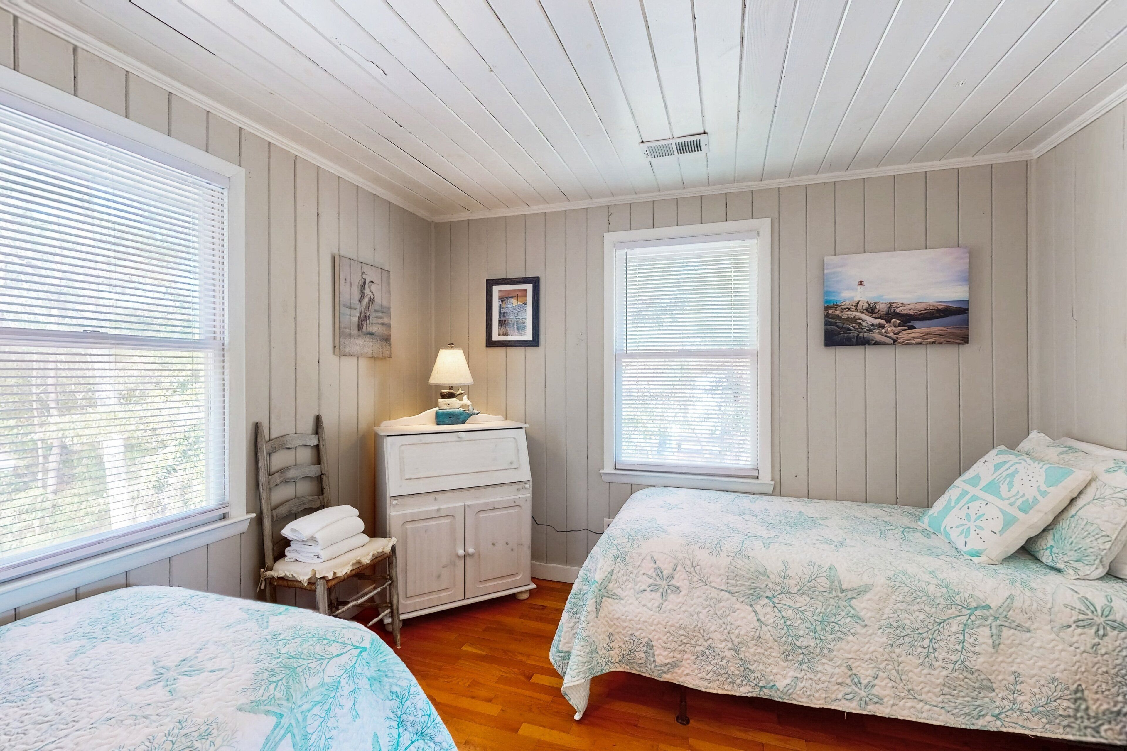 Un dormitorio con dos camas, pisos de madera y un aparador.