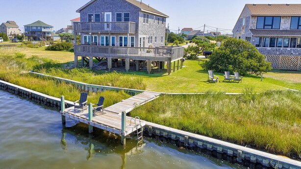 A waterfront property with a wooden deck, a grassy lawn, and a house with a balcony. - Sound FX 437: Sound-front w/shared pool (Avon)