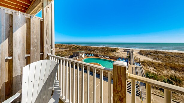 A wooden deck with a pool and beach view. - Darling oceanfront condo with outdoor pool, hot tub, balcony & views (Hatteras)