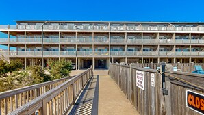 A multi-story hotel with a wooden deck leading to the entrance, signs indicating no pets allowed, and a 'CLOSED' sign on the right. - Darling oceanfront condo with outdoor pool, hot tub, balcony & views (Hatteras)