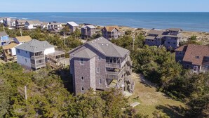 Un quartier résidentiel situé sur la côte, avec des immeubles à plusieurs étages, dont certains sont dotés de balcons, entouré d’arbres et offrant une vue sur l’océan.