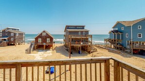 A beachside wooden structure with multiple decks and a staircase leading to the beach.