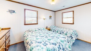A bedroom with two beds, a dresser, and two windows with blinds.