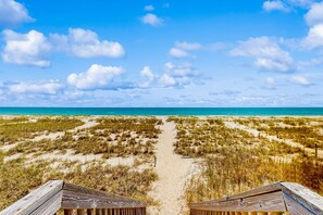 A beach path leading to the ocean with wooden structures at the end. - Oceanfront w/ beach access, amazing views, hot tub, kitchen, & smart TVs (Holden Beach)