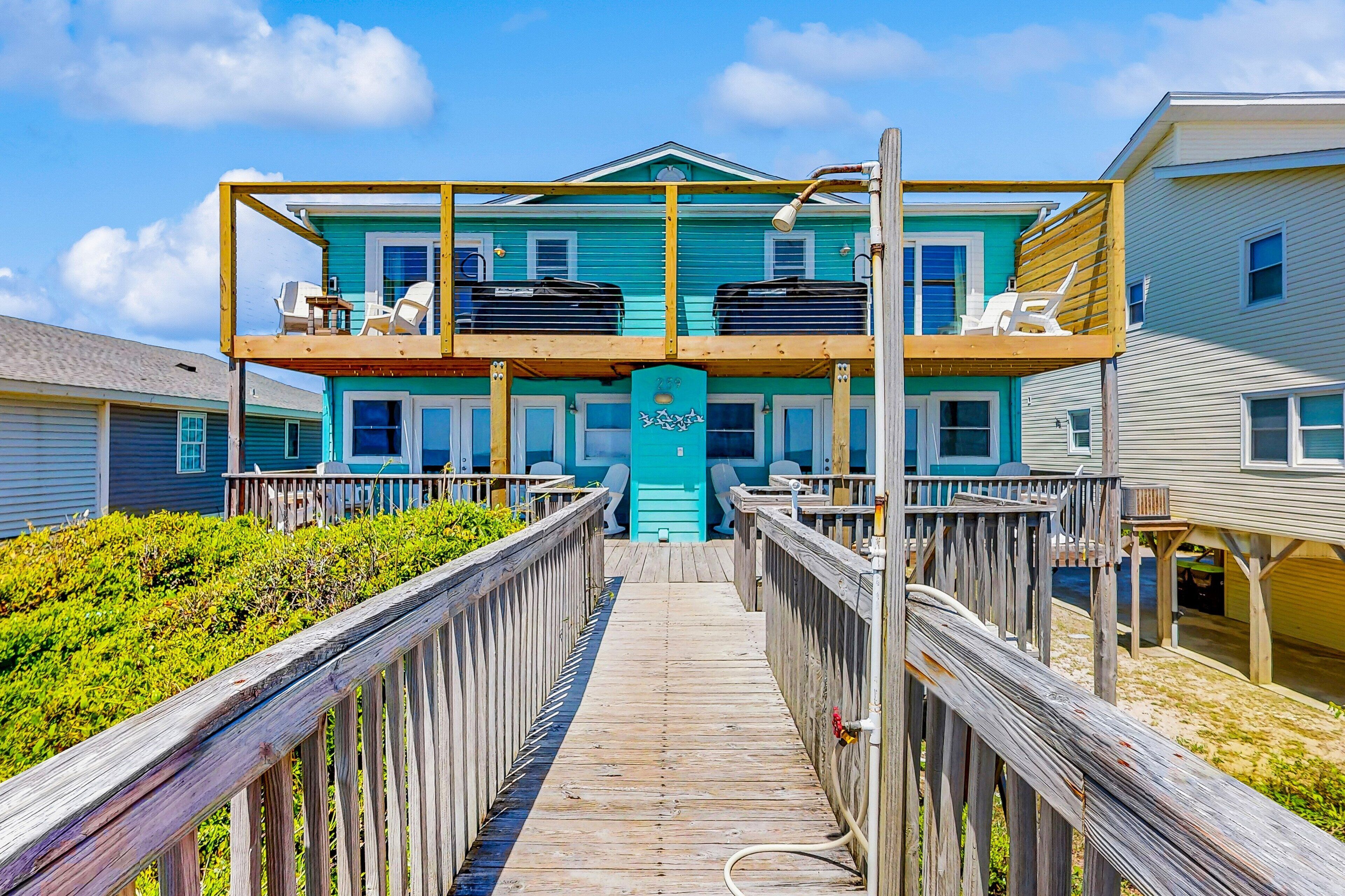 A two-story building with a wooden deck leading to a blue door.