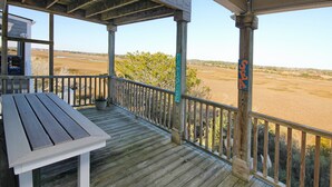 Un terrazzo in legno con tavolo e sedie, affacciato su un paesaggio naturale.