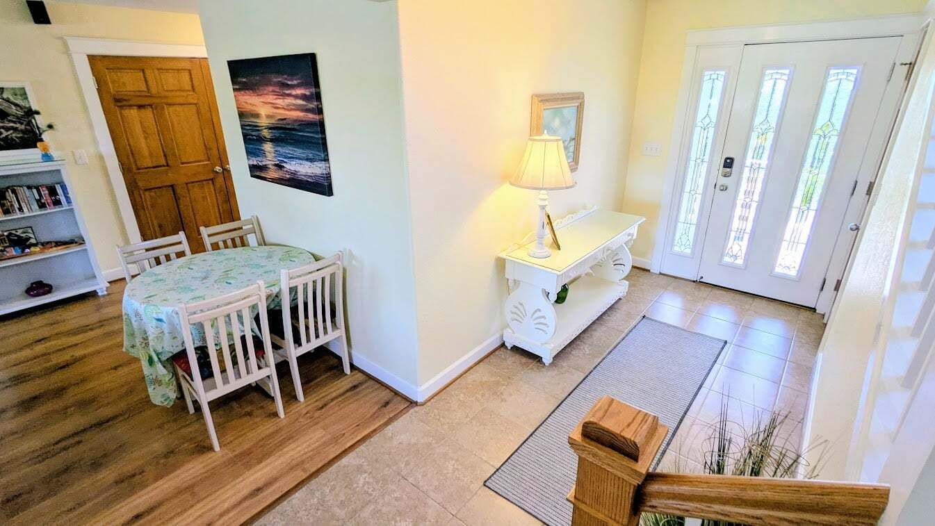 A dining area with a table and chairs, a lamp, a door with glass panels, and a mat on the floor.