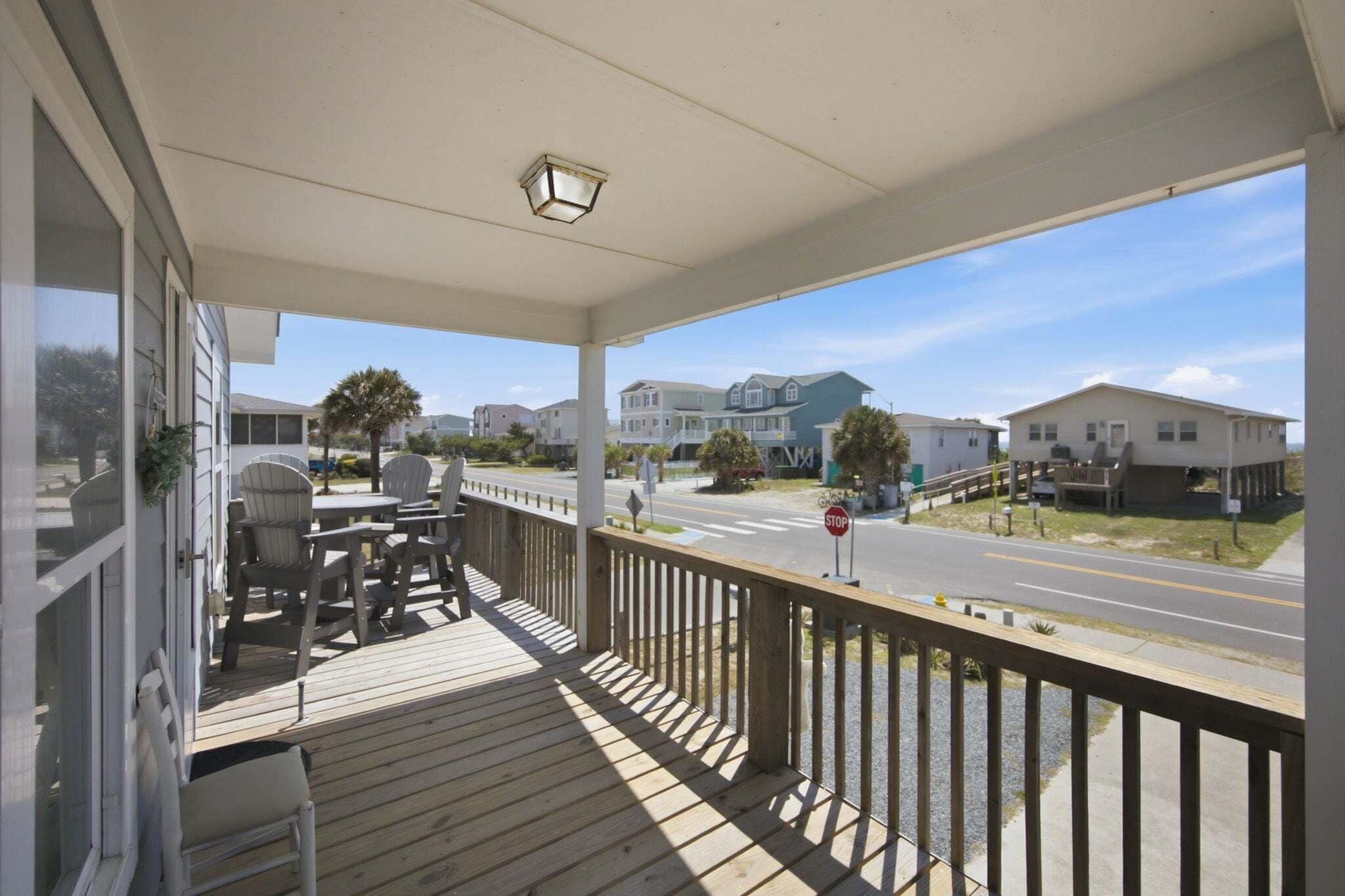 A wooden deck with outdoor furniture, a stop sign, and houses in the background.