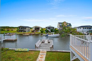 A waterfront property with a dock, boats, and houses with balconies.