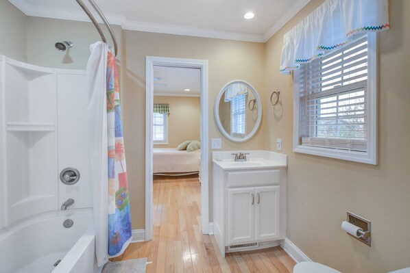 A bathroom with a bathtub, a shower, a sink, and a mirror.
