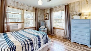 Ein Schlafzimmer mit Bett, Stuhl, Schminktisch und Deckenventilator.
