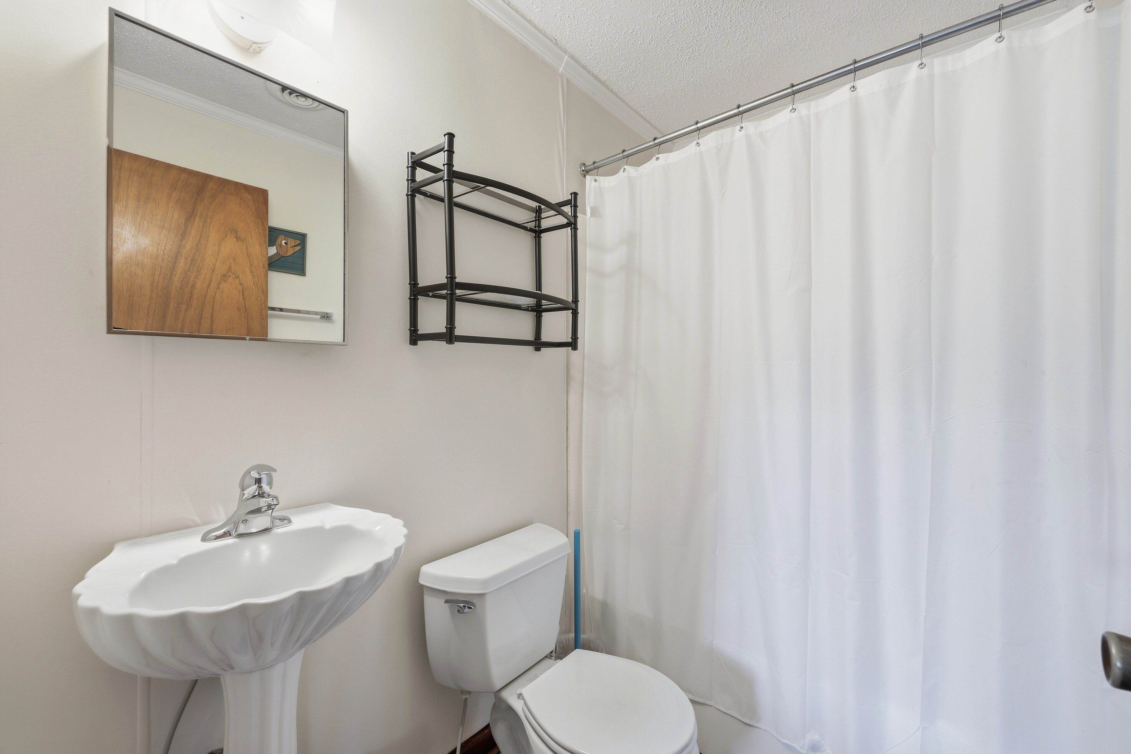 A bathroom with a white sink, toilet, and shower curtain.