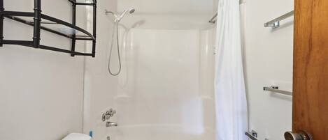 A bathroom with a shower, toilet, and a towel rack.