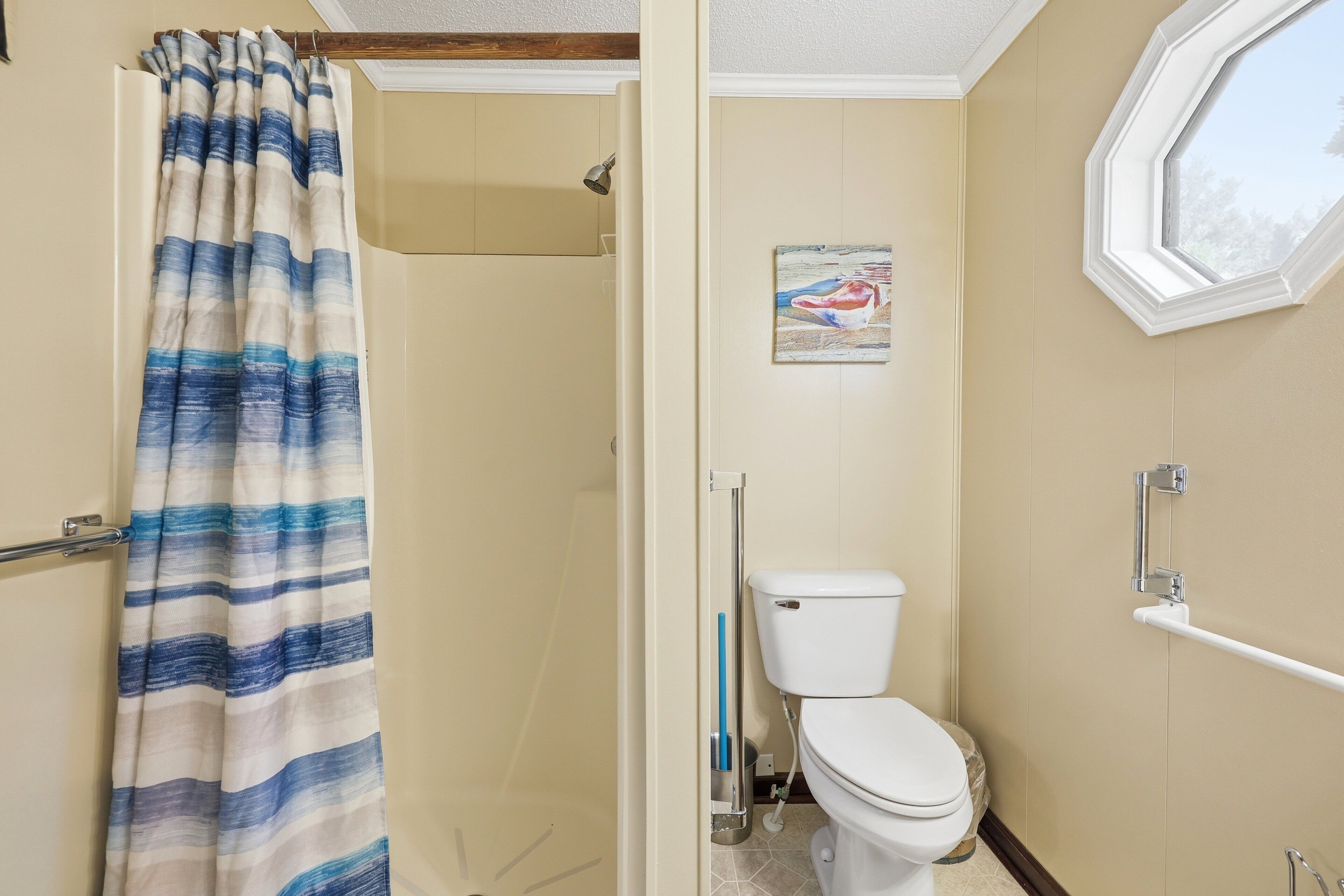 Une salle de bain avec un rideau de douche, des toilettes et une fenêtre.