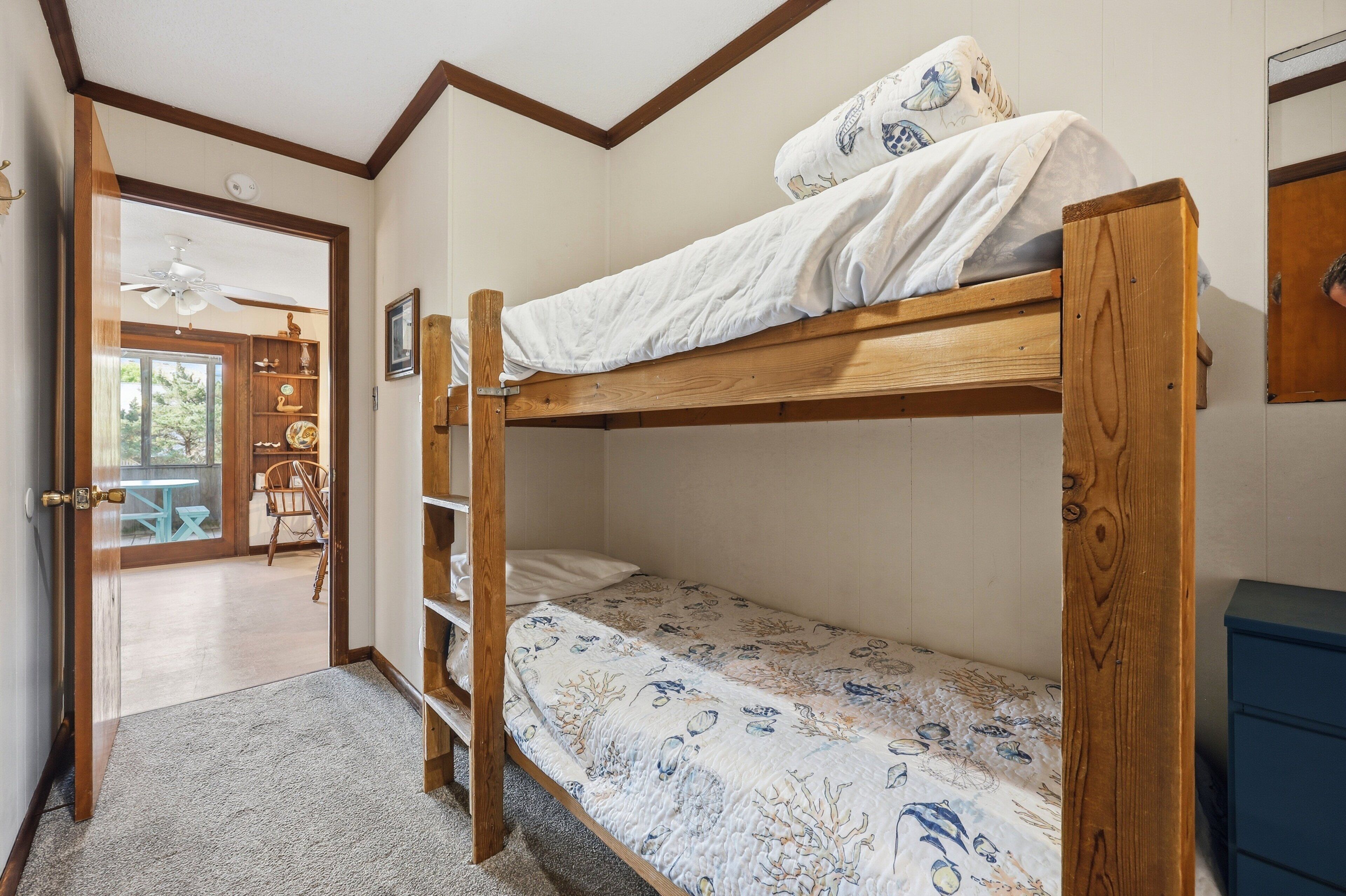 A bunk bed with a lower bunk, a wooden headboard, and a patterned bedspread.