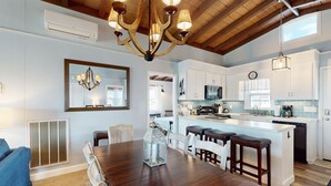 A spacious kitchen with white cabinets, a central island with stools, and a chandelier.