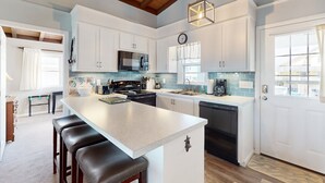 A modern kitchen with white cabinets, a large island, and a hanging light fixture.