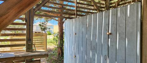 Une structure de pergola en bois, agrémentée d’une clôture en métal, d’un banc en bois et offrant une vue dégagée sur les environs.
