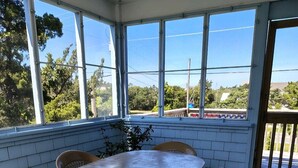 Un patio coperto con un tavolo rotondo e quattro sedie, ampie finestre e vista sul panorama esterno.