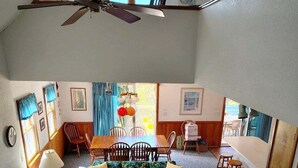 Un accogliente soggiorno con ventilatore a soffitto, un divano, un tavolino da caffè e un'area pranzo con sedie.