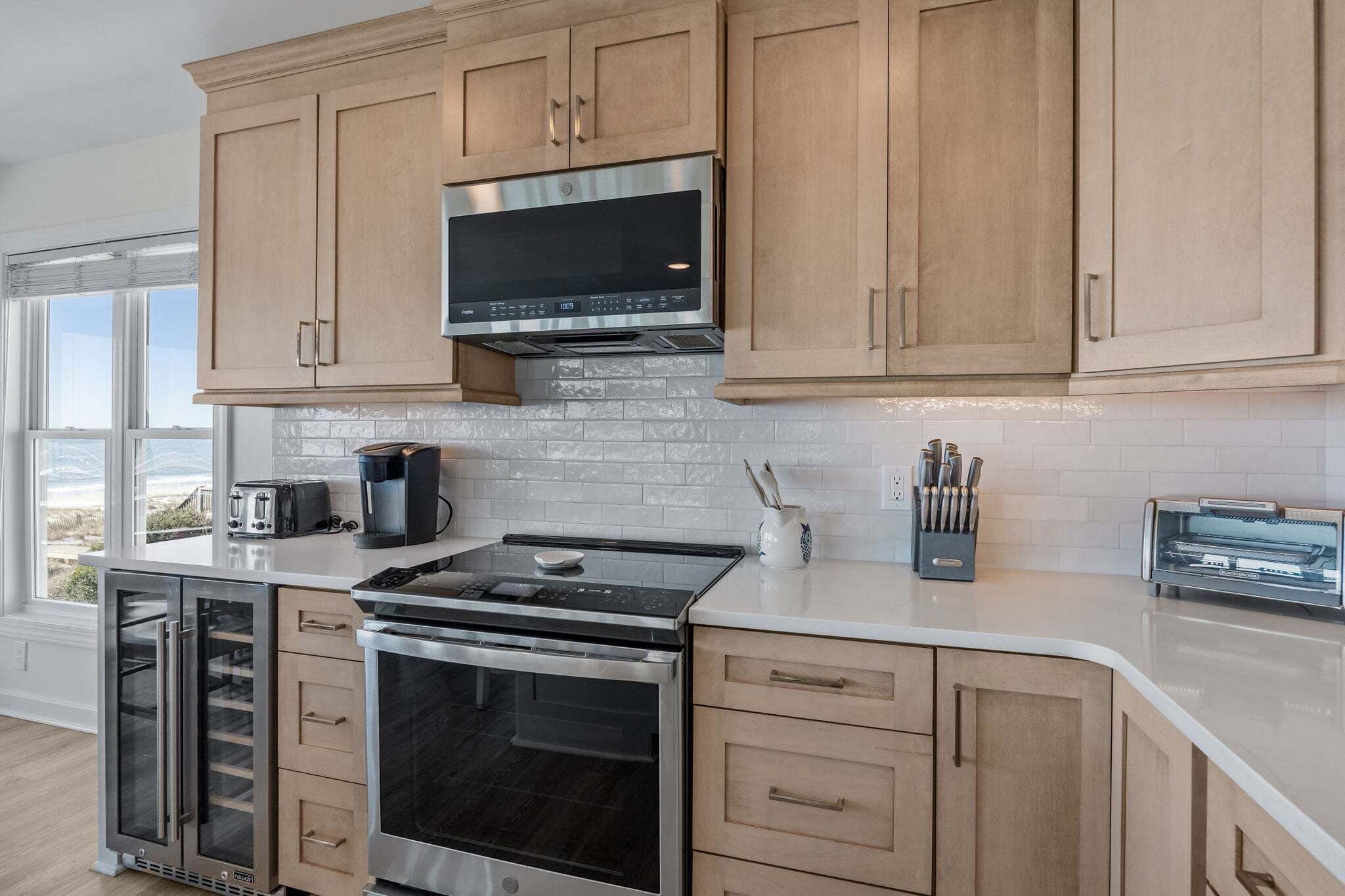 A modern kitchen with stainless steel appliances, wooden cabinets, and a view of the outdoors.
