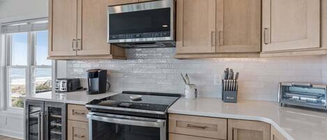 A modern kitchen with stainless steel appliances, wooden cabinets, and a view of the outdoors.