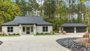 Et toetagers hus med garage, omgivet af en anlagt indkørsel og et skovområde.