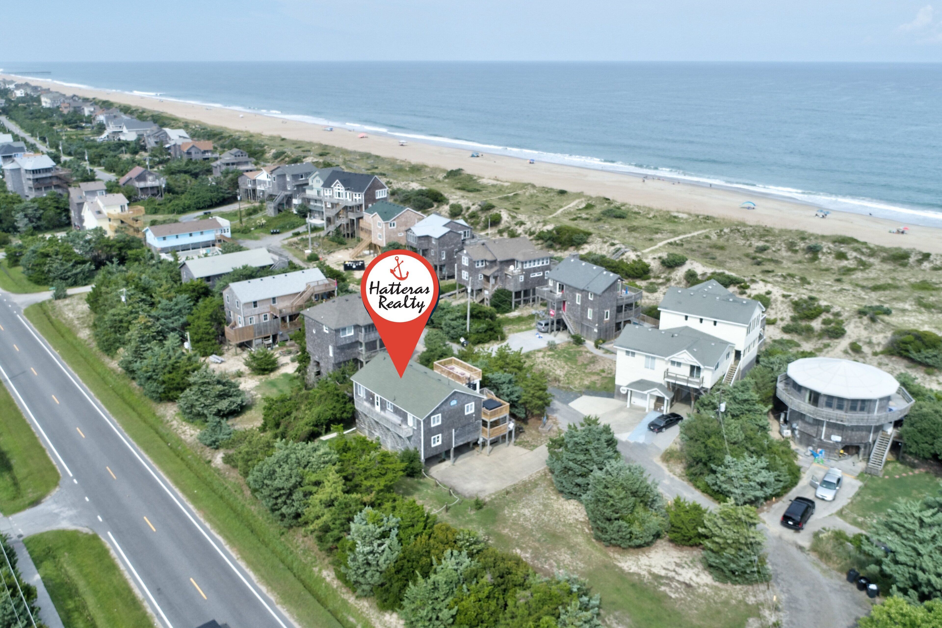 Ein Luftbild eines Küstenwohngebiets mit Häusern, einem Strand und einer Straße.