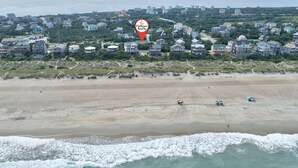 An aerial view of a coastal residential area with houses, a beach, and ocean waves. - Twin Tides #14-AC: Semi-Oceanfront, Dog-Friendly, Shared Pool, Hot Tub (Avon)