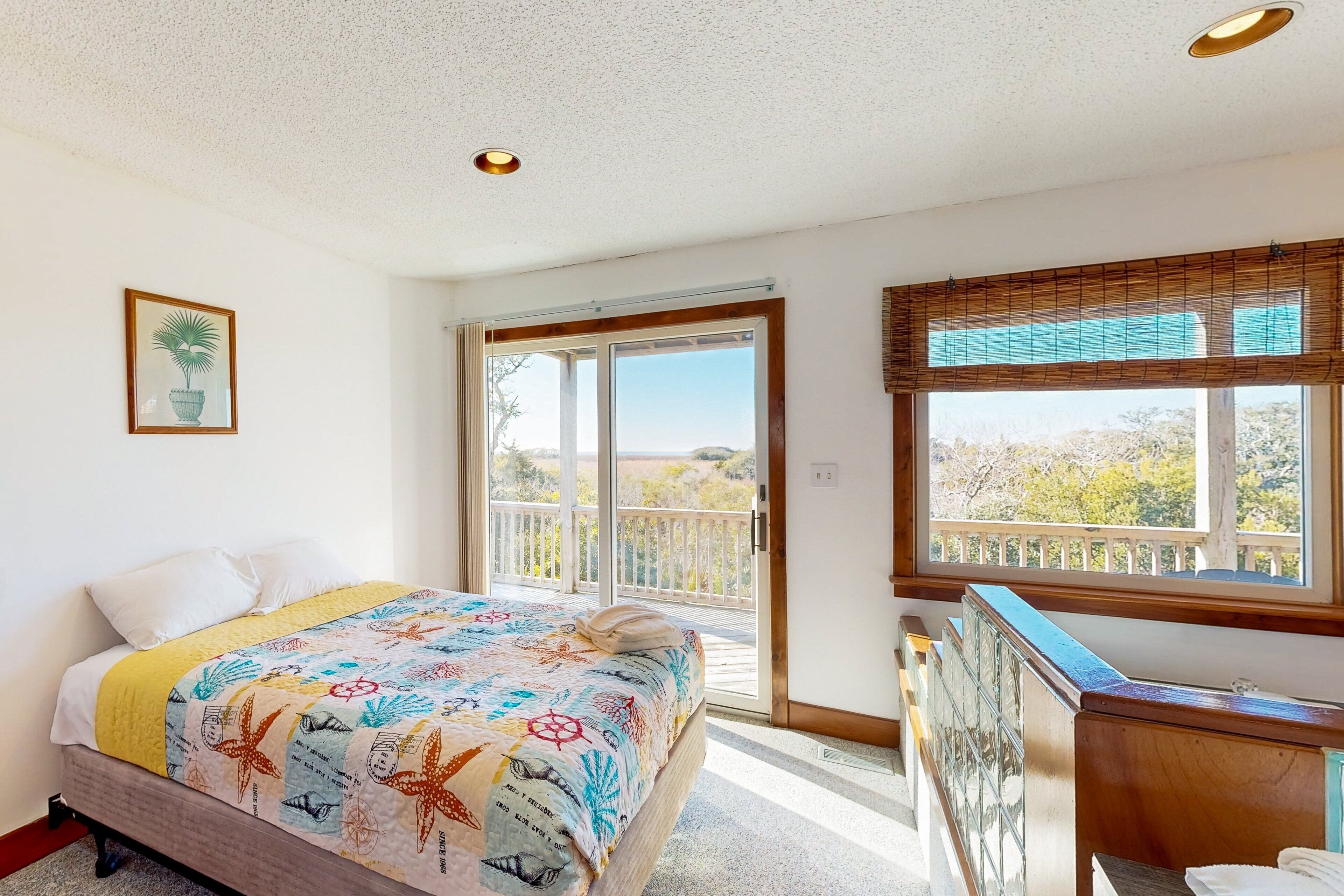 A bedroom with a bed, a window with a view, and a door leading to an outdoor balcony.