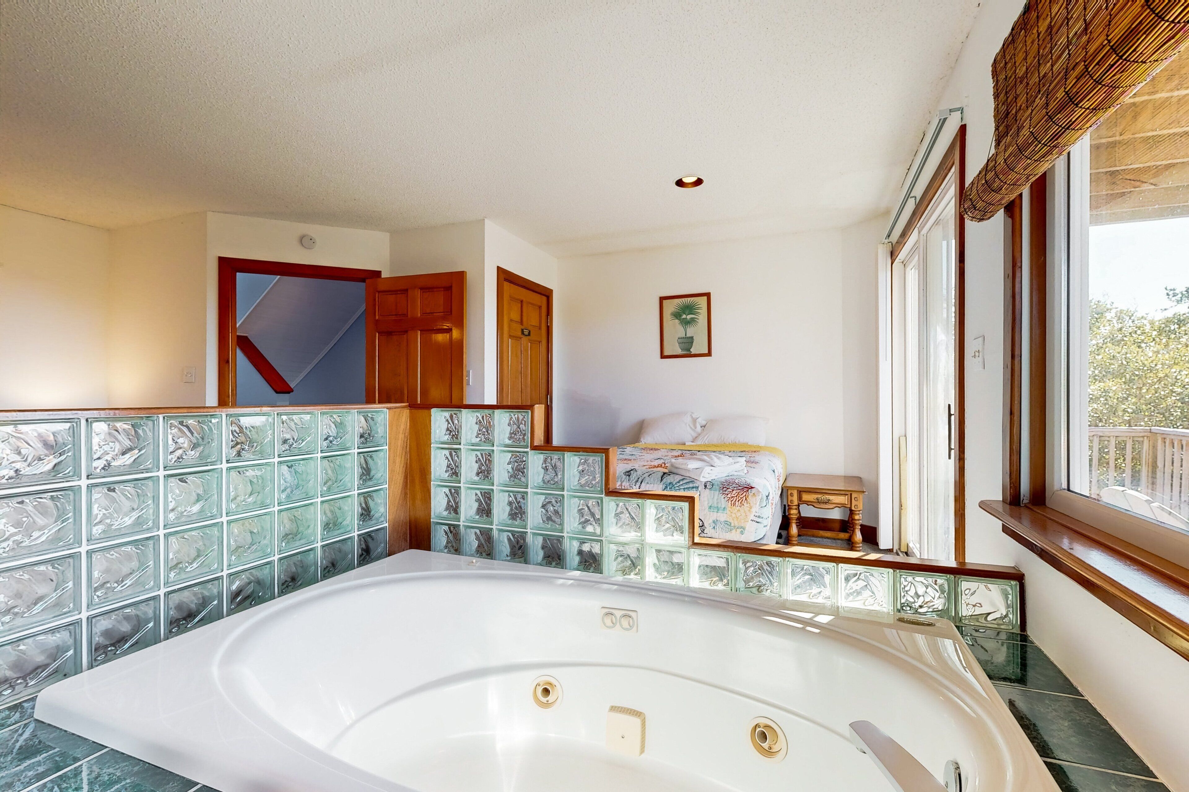 Un bagno con una vasca da bagno ampia, uno spazio doccia e una finestra con vista sull'esterno.