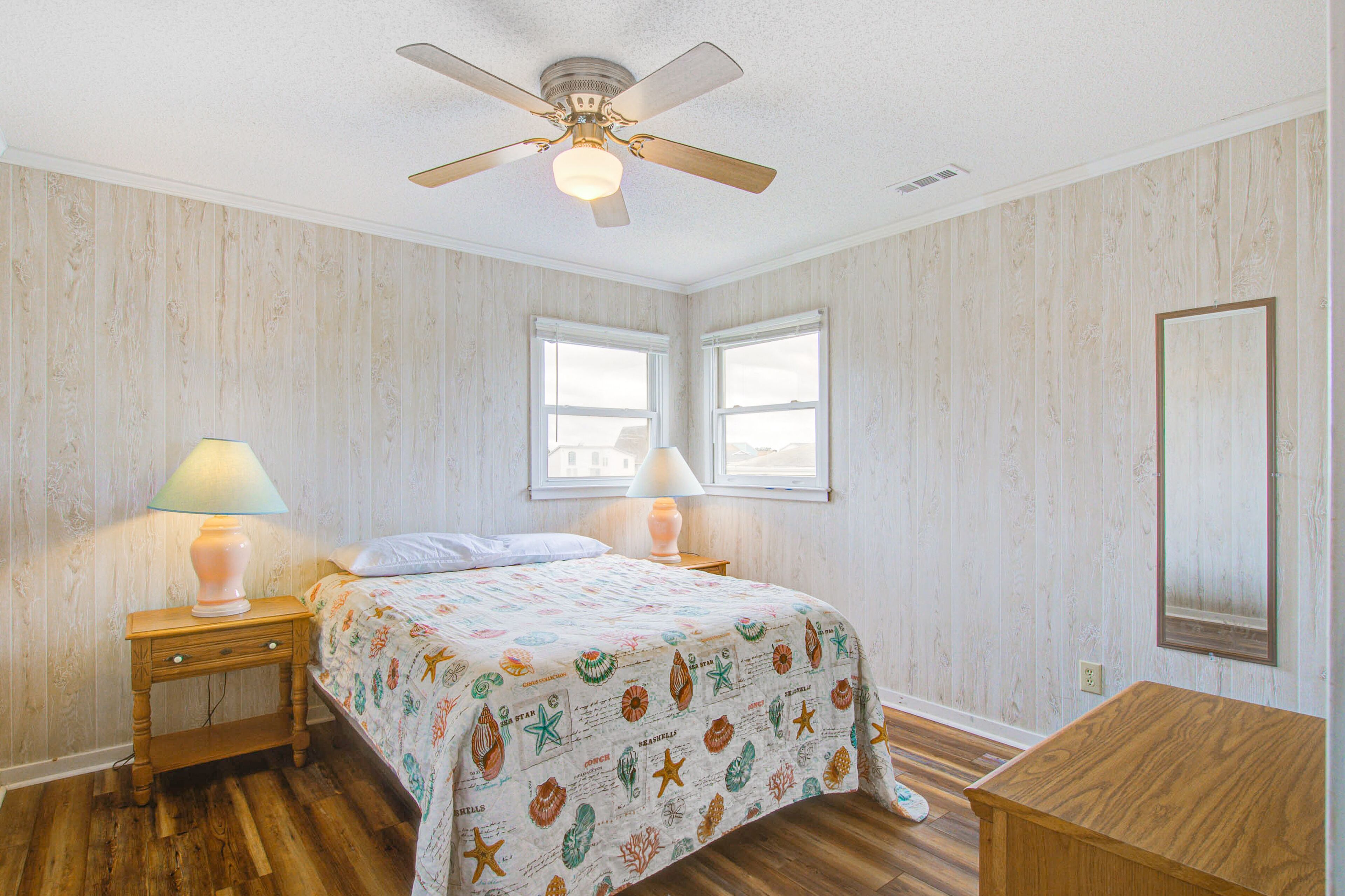A bedroom with a bed, two bedside lamps, a ceiling fan, and a wooden nightstand.
