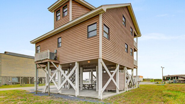 A two-story building with a balcony and a covered patio area. - Shiloh by the Sea: Ocean-View Home with Easy Beach Access, WiFi & Central AC (Holden Beach)