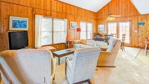 Un intérieur de chalet chaleureux avec des murs en bois, un téléviseur, un canapé et un coin repas.