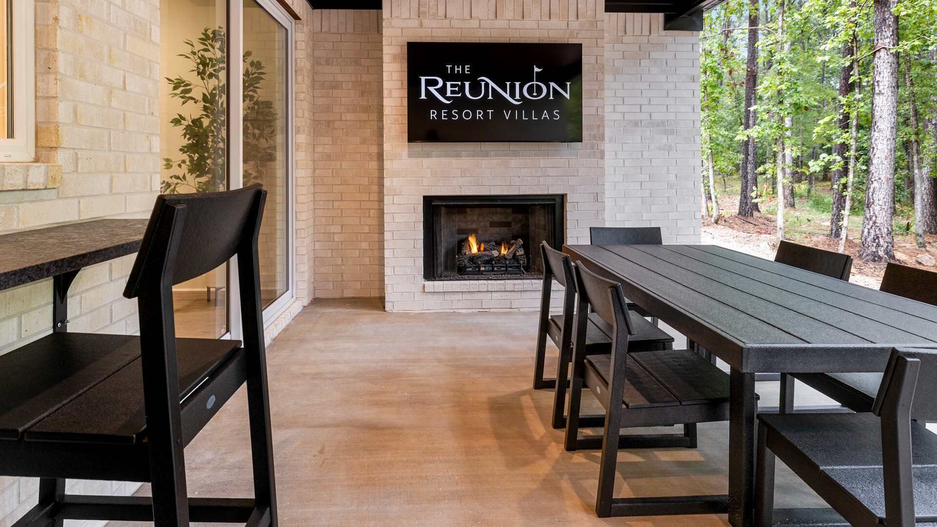 Ein gemütlicher Sitzbereich im Freien mit Kamin, Holzbänken und einem Schild mit der Aufschrift 'The Reunion Resort Villas'.